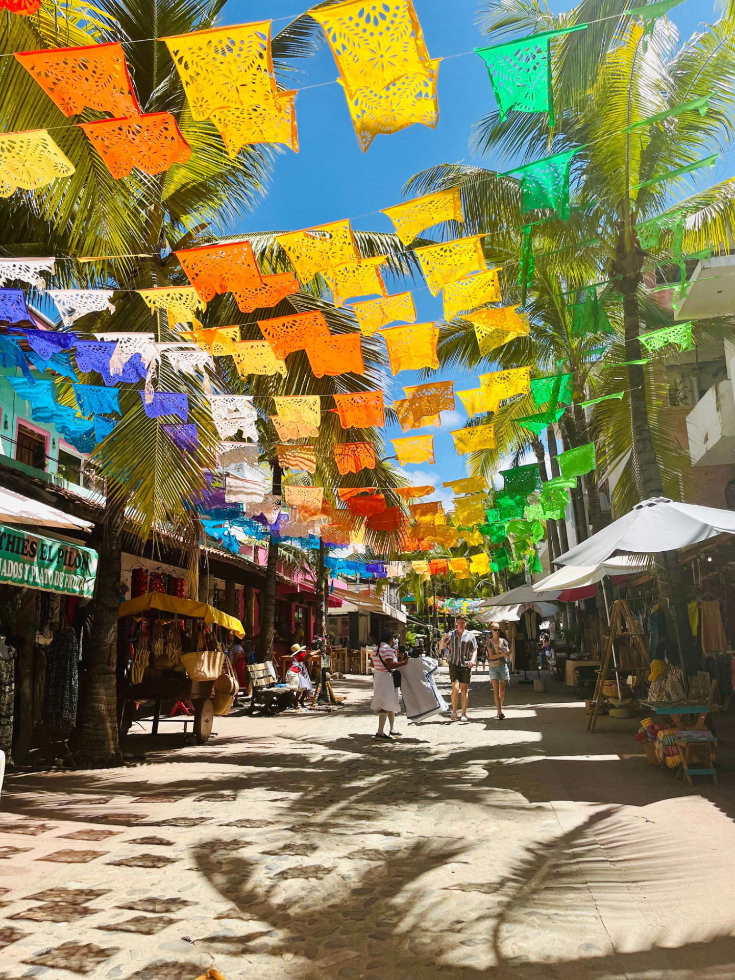 Calle colorida de Playa del Carmen con banderines de papel picado y palmeras