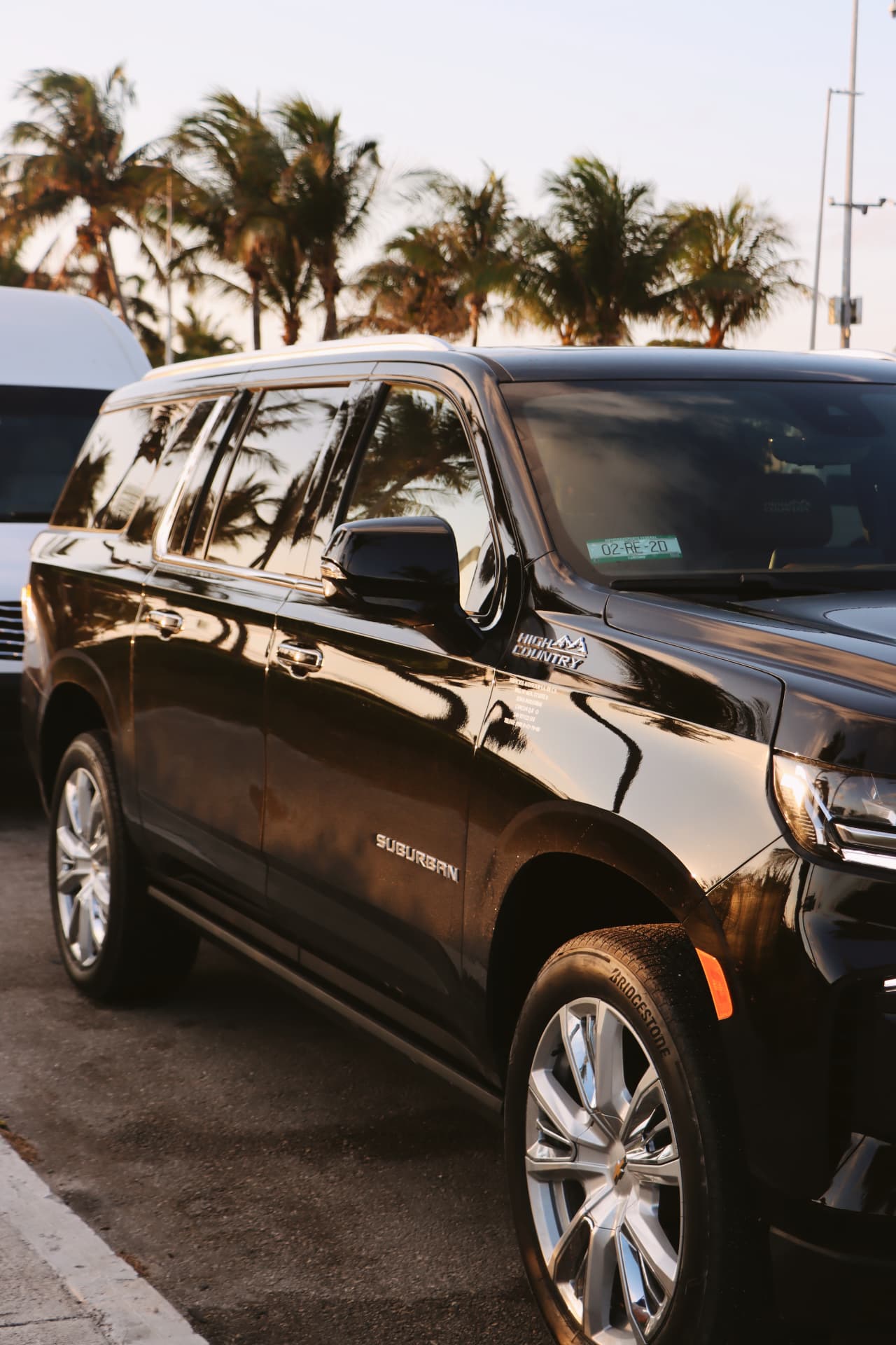 Suburban High Country negra junto a van blanca al atardecer