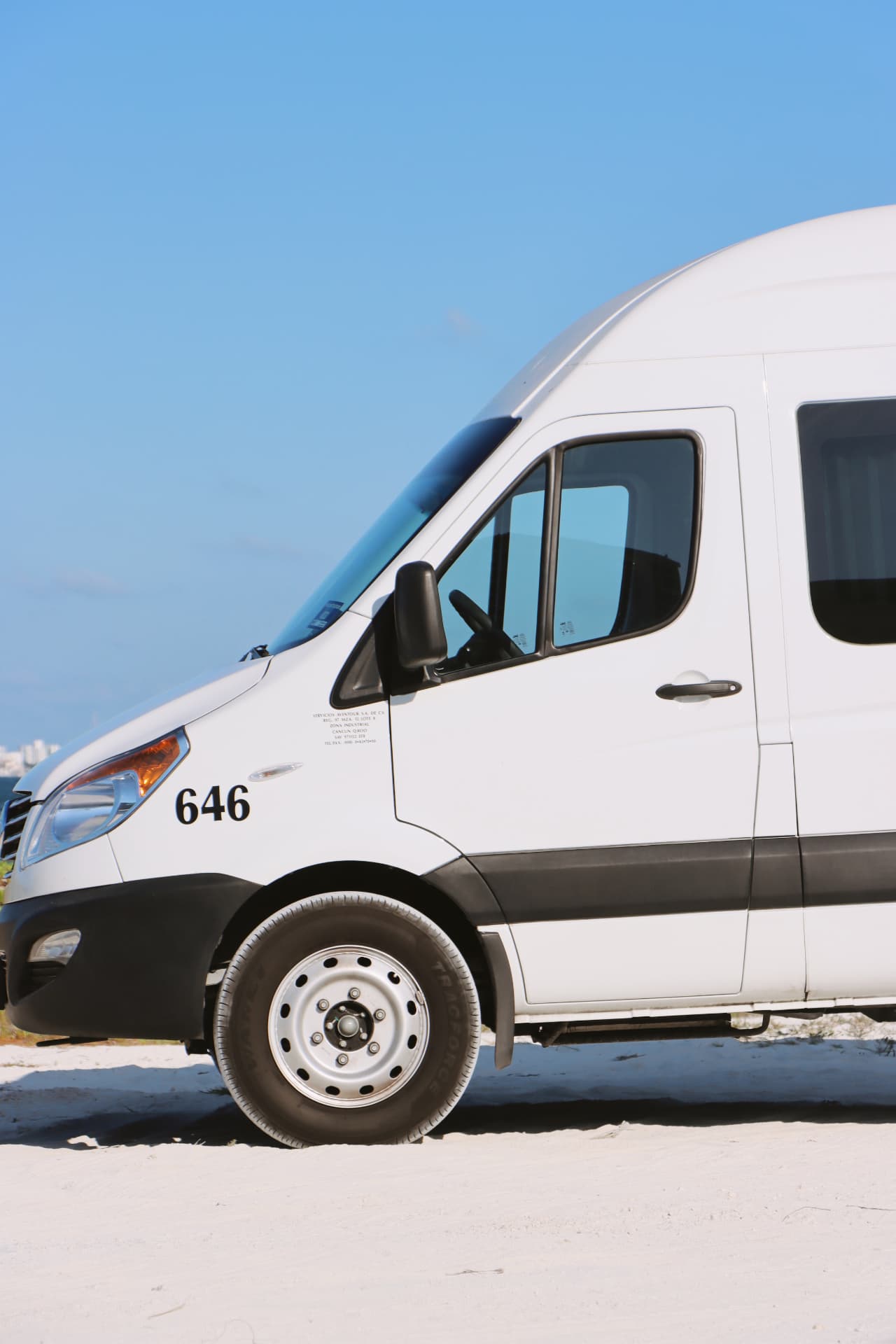 Van JAC blanca estacionada en la playa de arena blanca
