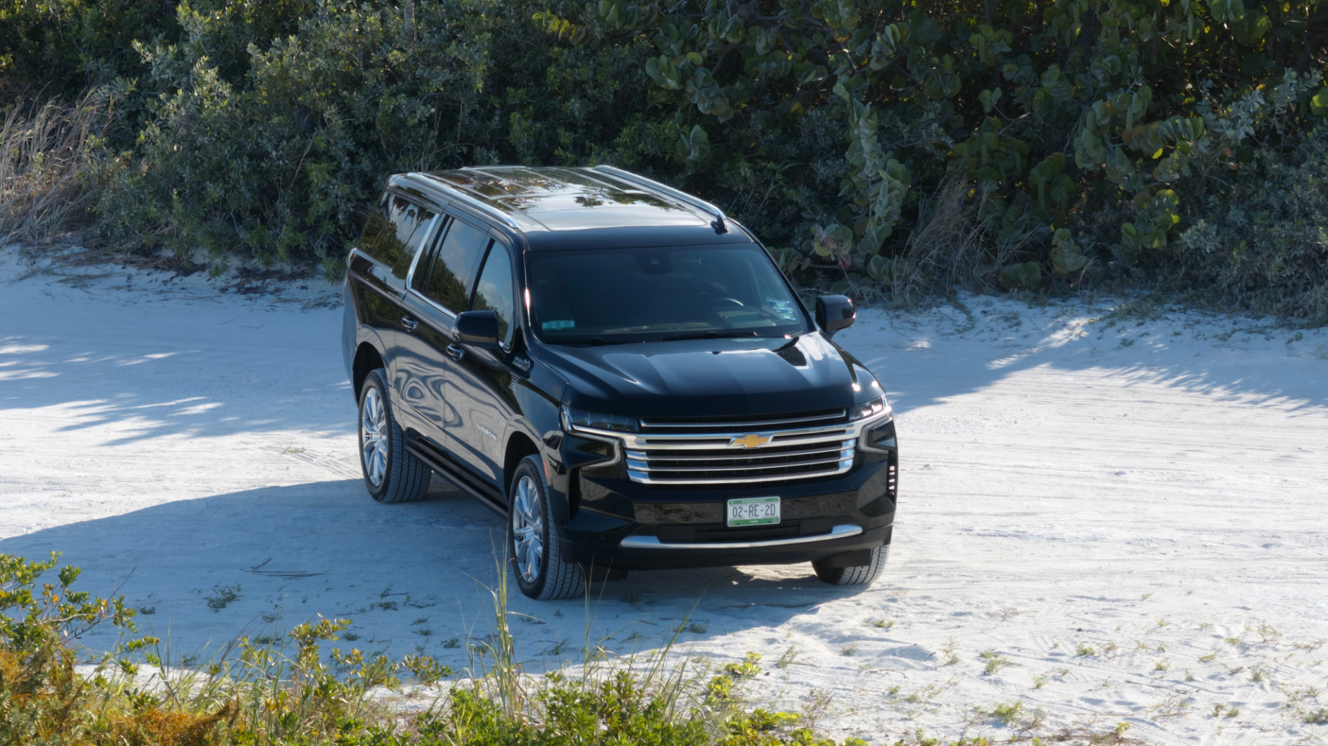 Chevrolet Suburban negra en un camino de arena blanca